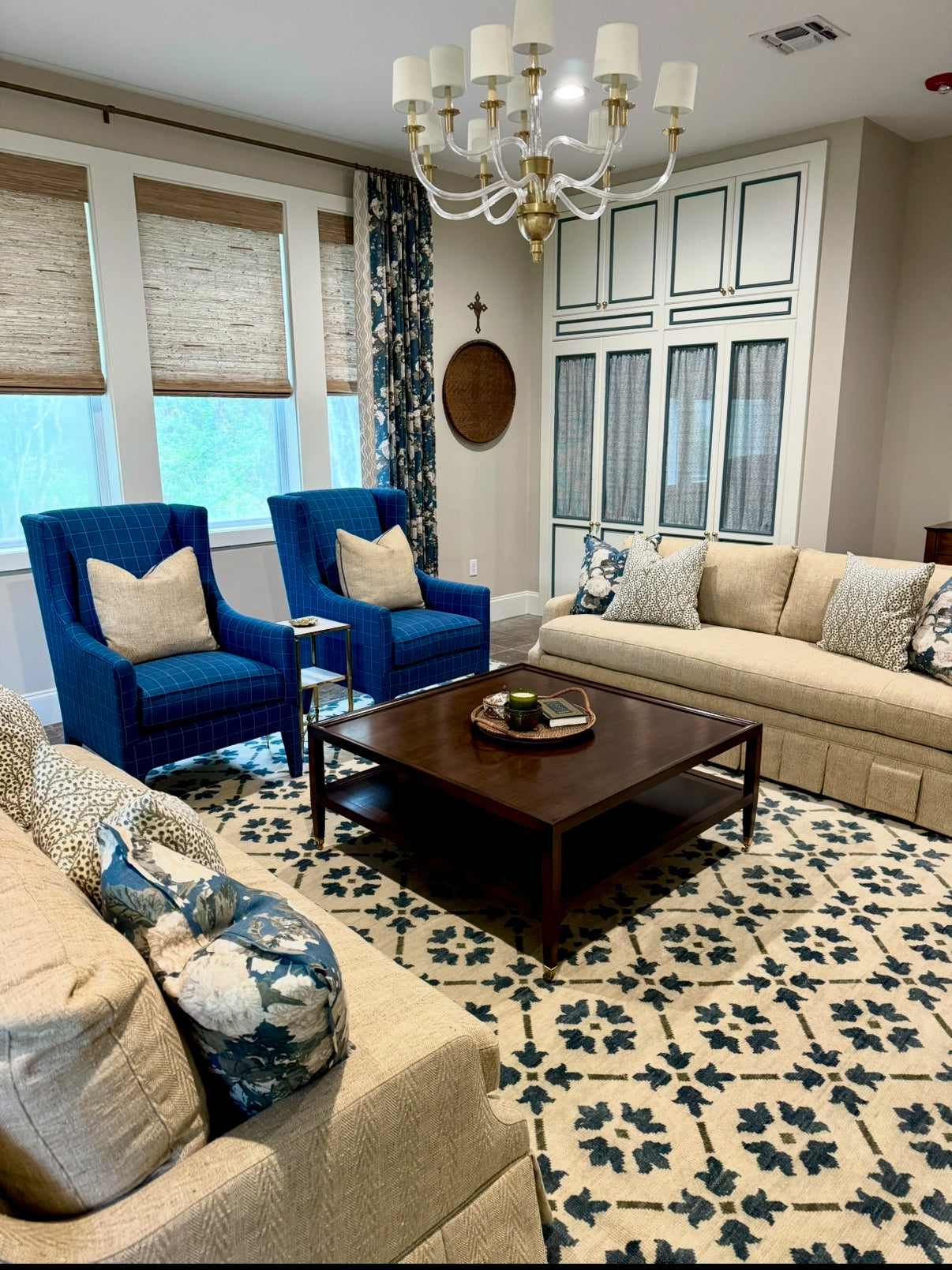 Living room with blue chairs, beige sofa, and geometric modern oushak blue and green rug.