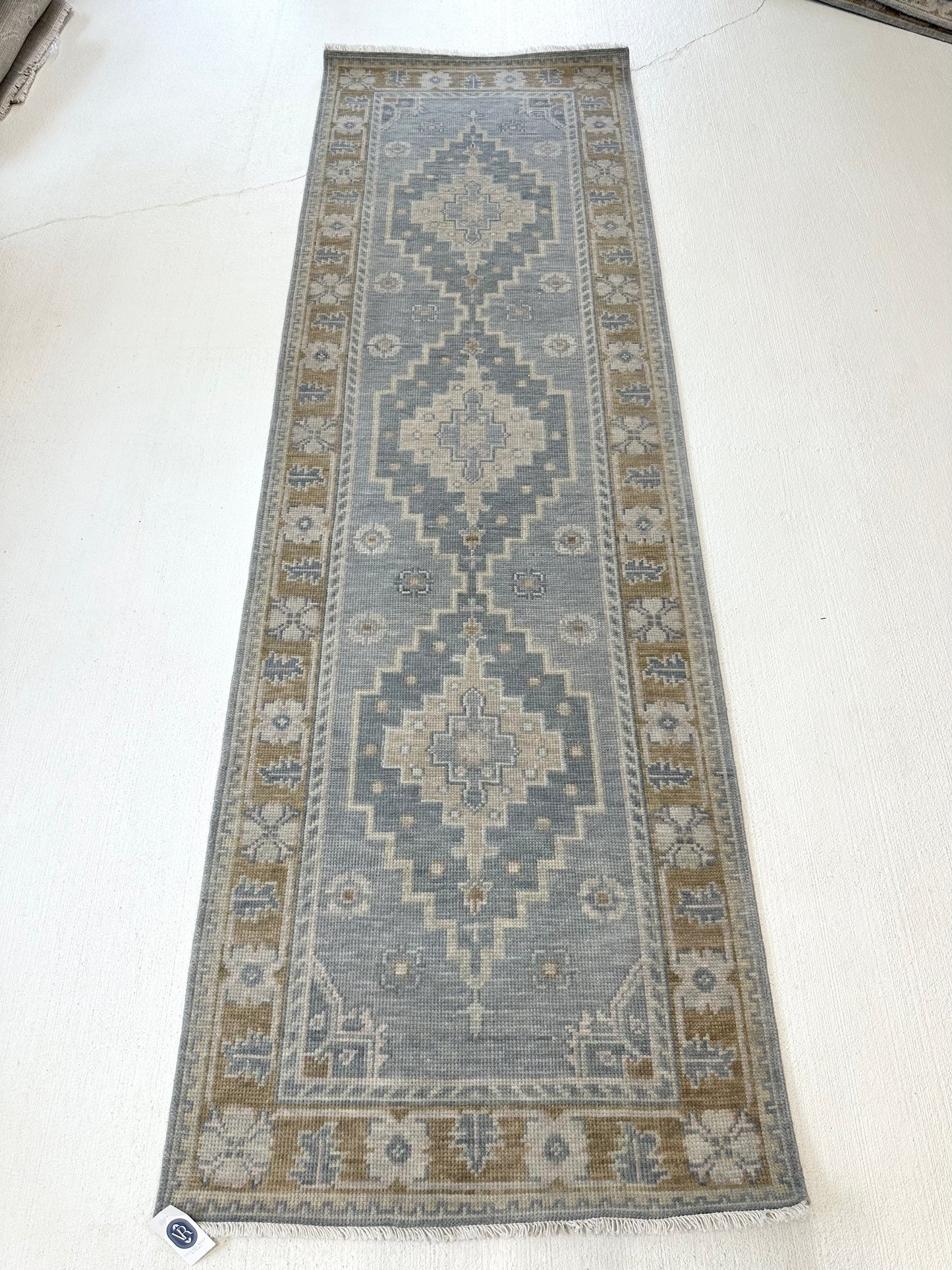 Blue modern oushak rug runner with accents of darker gray-blue, tan, cream, and brown border in kitchen that is In a home in Southern Living Magazine.