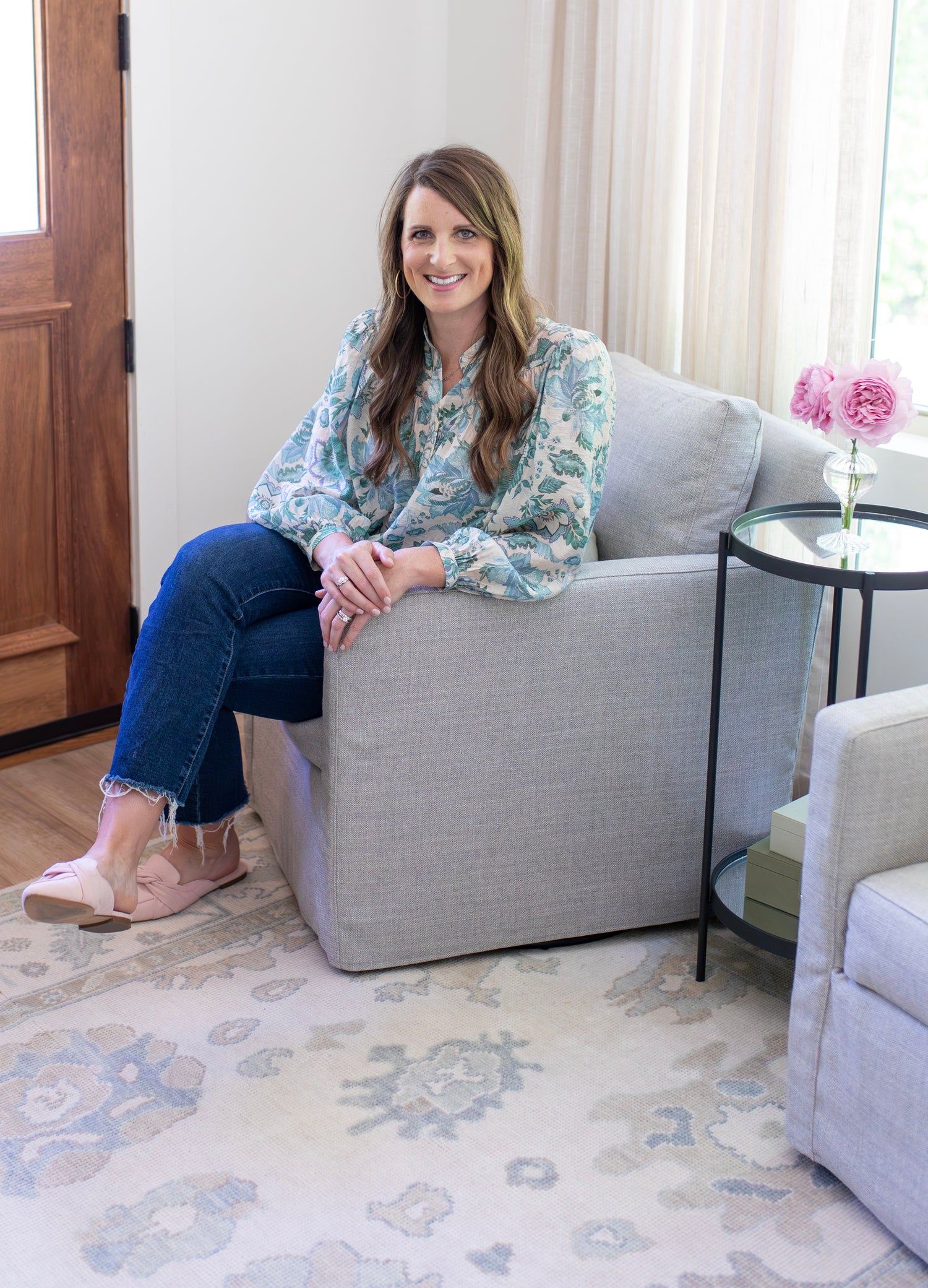 Owner of company sitting in chair on top of cream colored hand-knotted modern oushak rug.