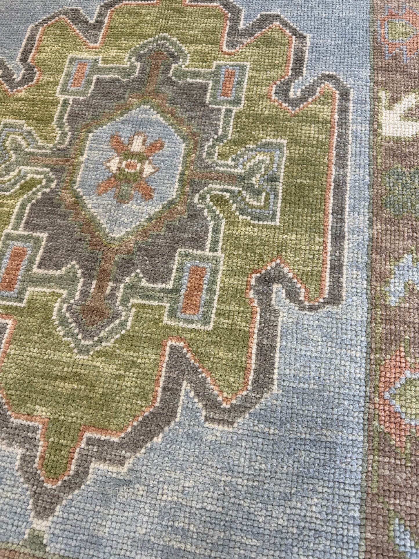 Close-up of a patterned turkish oushak blue and green rug with geometric design