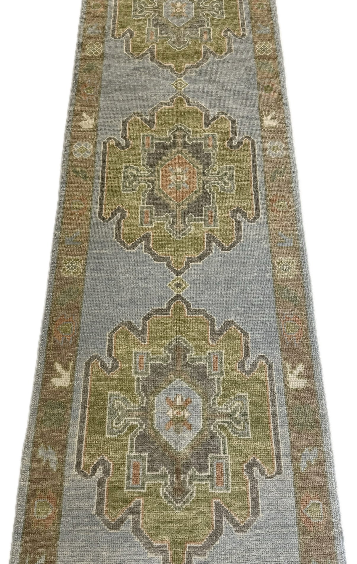 Blue and green turkish hand-knotted runner rug with geometric pattern on a plain background