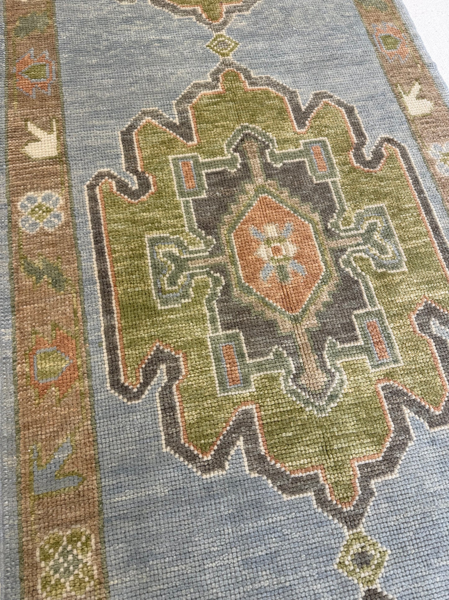 Close-up of a blue and green patterned oushak rug with geometric design that is hand-knotted