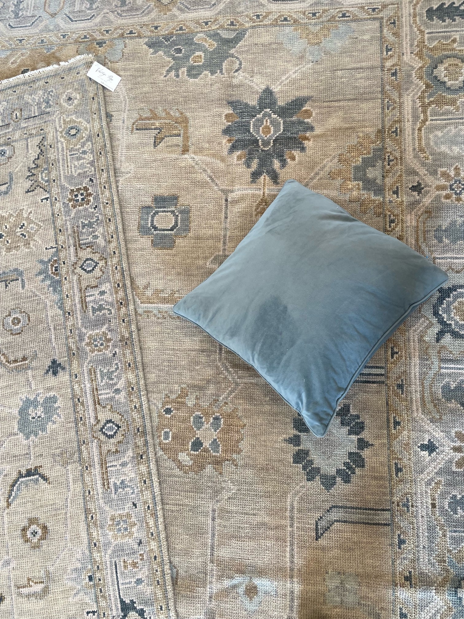 Neutral Turkish Oushak with blues with blue velvet pillow placed on top.