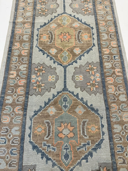 Gemma Turkish Oushak rug styled in a room, light aqua, turquoise, coral, brown, cream, green, hand-knotted wool