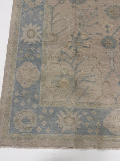 Ophelia warm neutral modern Oushak rug with a soft light blue border and sage green, brown, and cream accents, hand-knotted wool