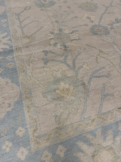 Ophelia hand-knotted wool modern Oushak rug in warm neutral with a light blue border and sage green and cream tones