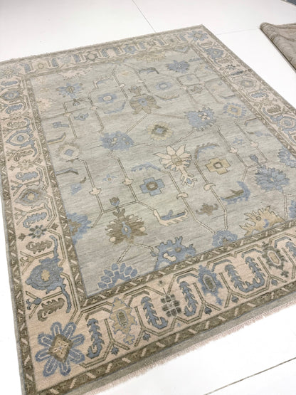 Lucy modern Oushak rug with a seafoam green base, cream border, and green, brown, light blue, and taupe accents, hand-knotted wool