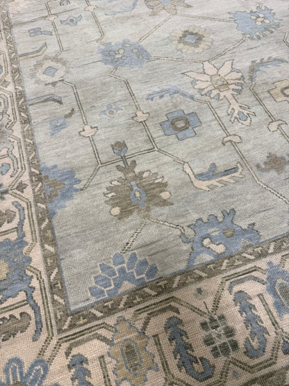 Lucy hand-knotted wool modern Oushak rug in a seafoam green base, cream border, and green, brown, light blue, and taupe accents