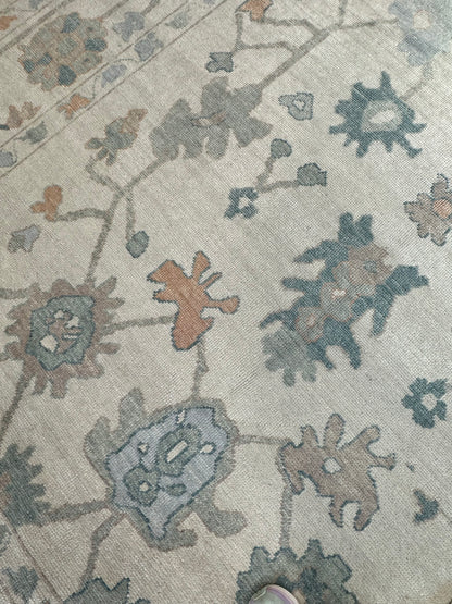 Olivia hand-knotted wool Turkish Oushak rug in off-white with teal, muted orange, and earthy brown tones
