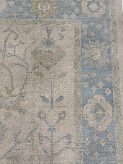 Ophelia modern Oushak rug, warm neutral with light blue border and sage green, brown, and cream accents