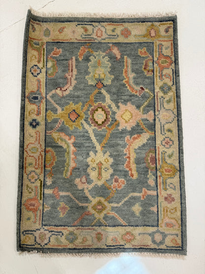 Madeline hand-knotted wool modern Oushak rug in a blue foundation, sage border, and olive, navy, plum, pink, salmon, gold, and cream accents