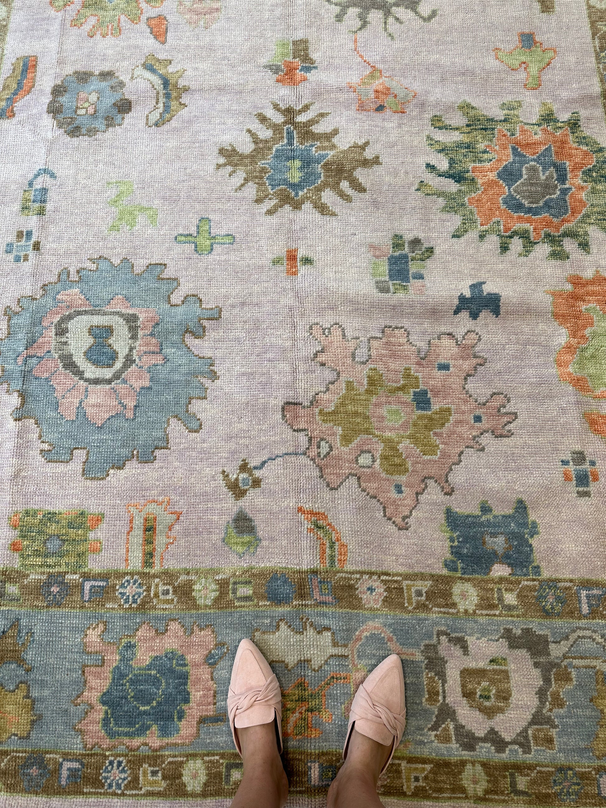 Colorful wool turkish oushak rug with blues, greens, pink, orange, and lavender.