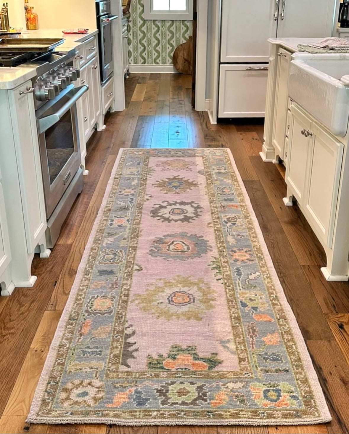 Bailey colorful turkish oushak runner rug with blues, greens, lavender, orange in kithcen with green wallpaper and white cabinets in Fairhope, AL.