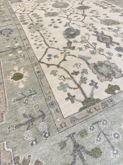 Close-up of a patterned blue and green Turkish Oushak rug with floral designs on a neutral background