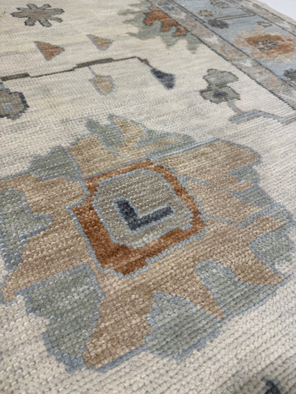Close-up of Lottie Turkish Oushak  Wool rug with geometric design and colors tan, green, light blue, navy, and coral