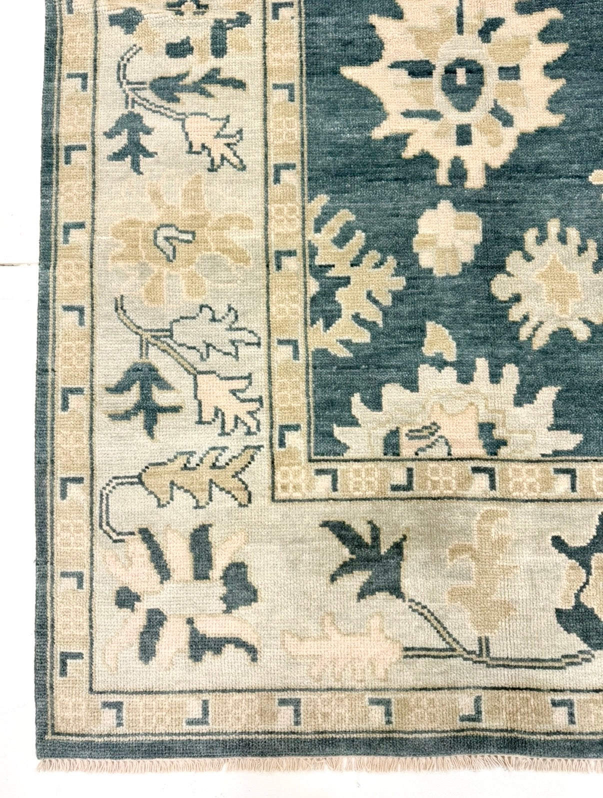 Corner of Lucille features a dark turquoise base, seafoam border, and cream and tan accents. Hand-knotted 100% wool oushak rug. In stock or made to order.