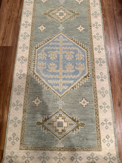 Lennon sage green modern Oushak rug with a cream border and blue and tan accents, hand-knotted wool