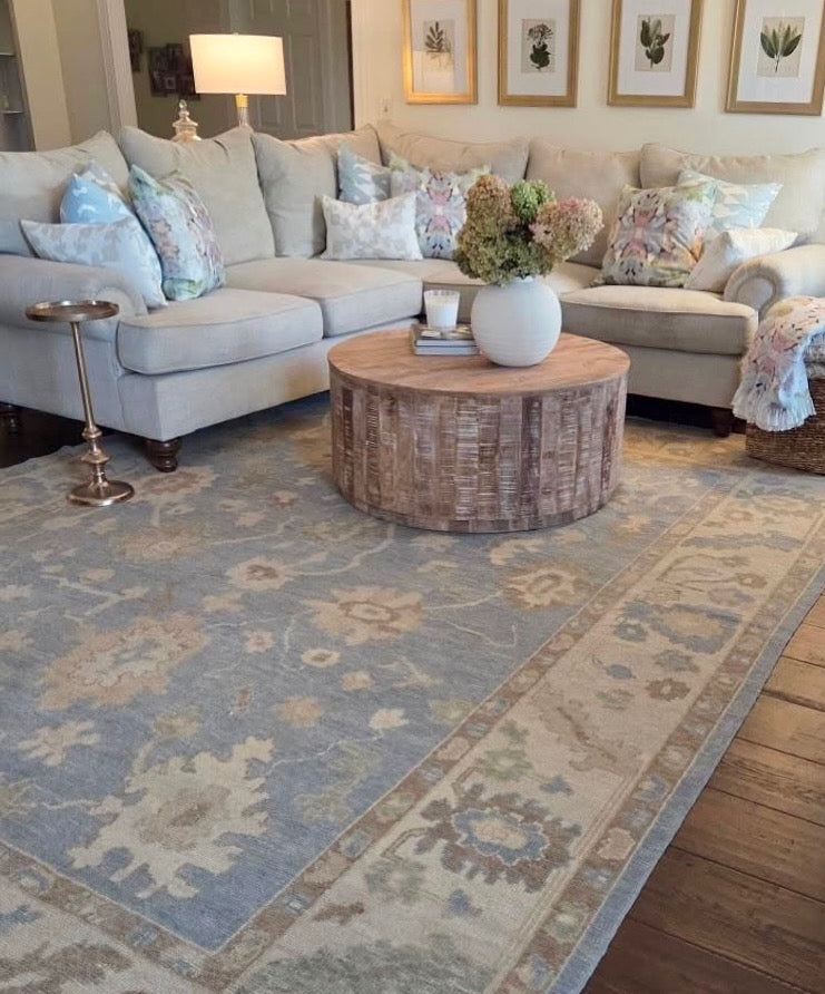 Living room with a sectional sofa, coffee table, and turkish oushak blue and green rug.