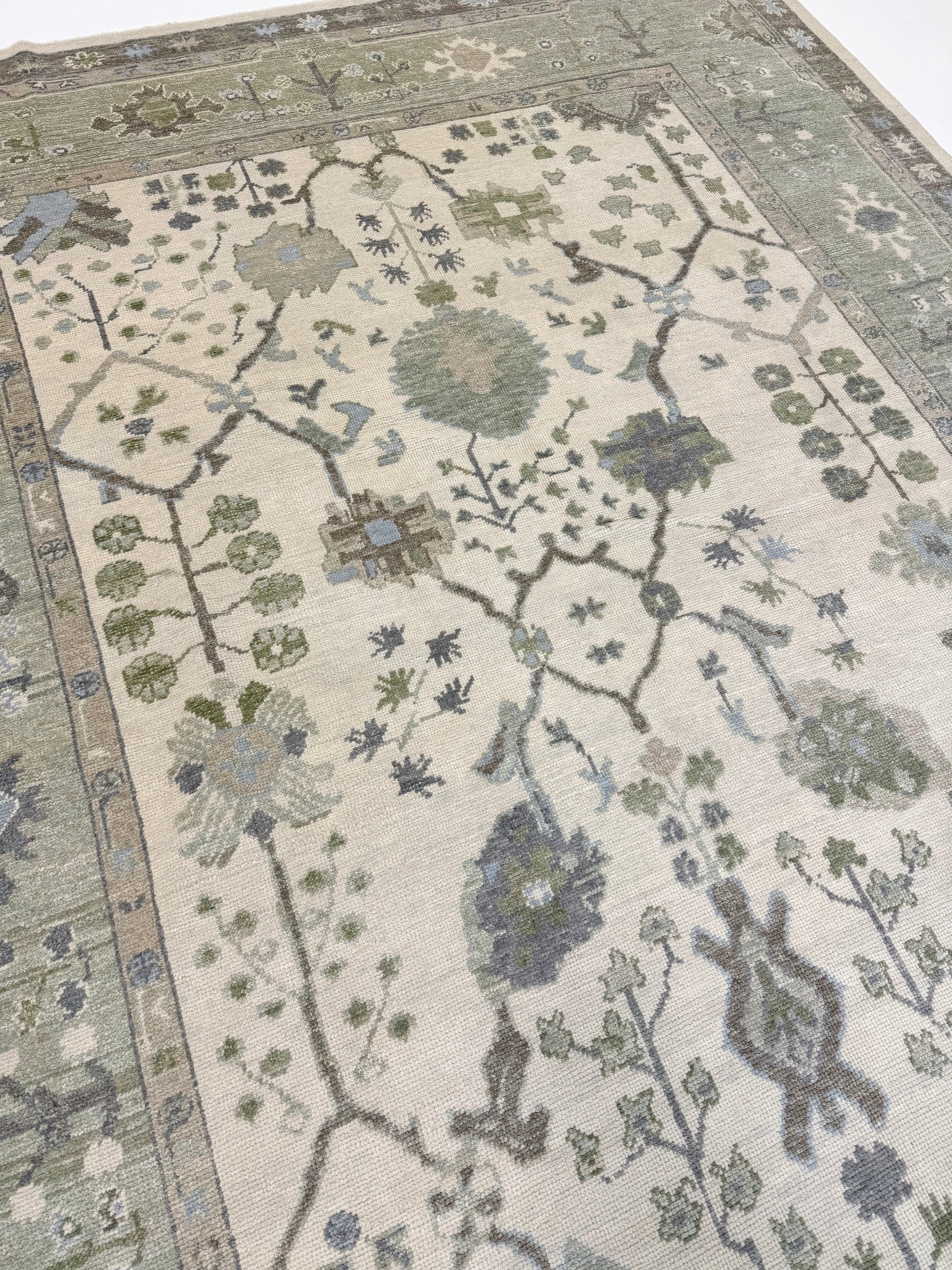 Turkish oushak rug with blues and greens and intricate patterns on a neutral background