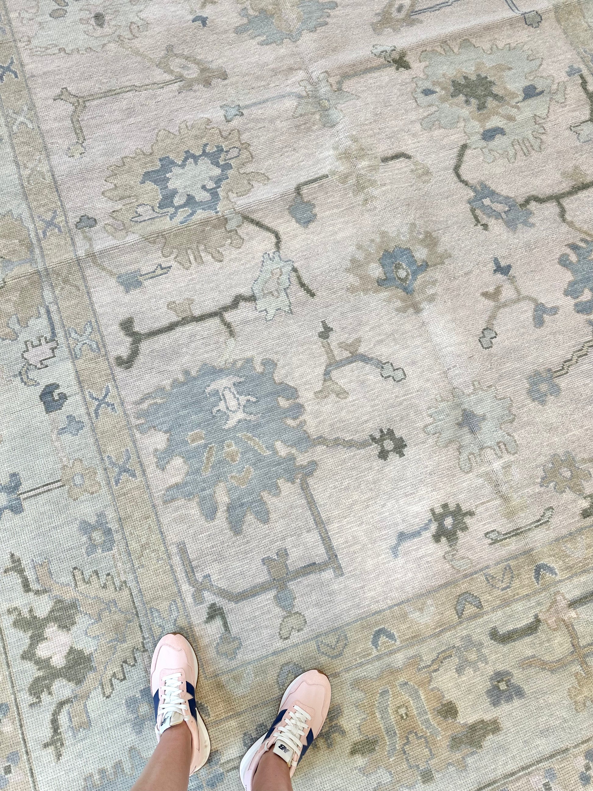 Modern Oushak Rug with blues and greens that is wool hand-knotted.  Pink shoes standing on modern oushak rug.