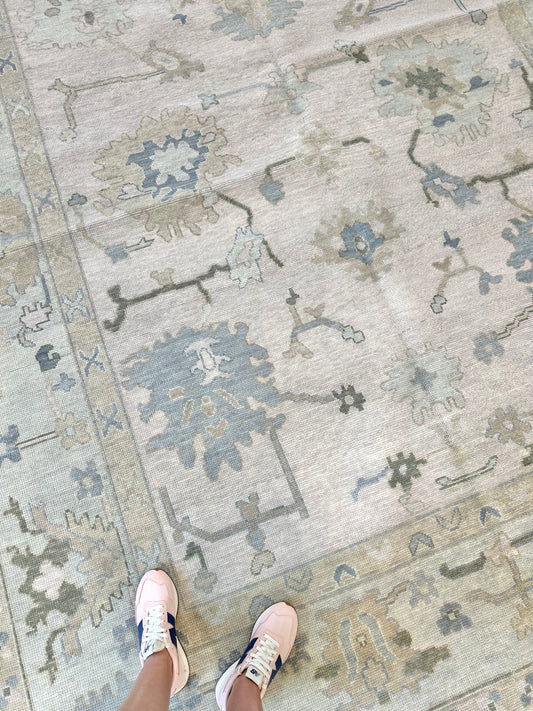 Modern Oushak Rug with blues and greens that is wool hand-knotted.  Pink shoes standing on modern oushak rug.