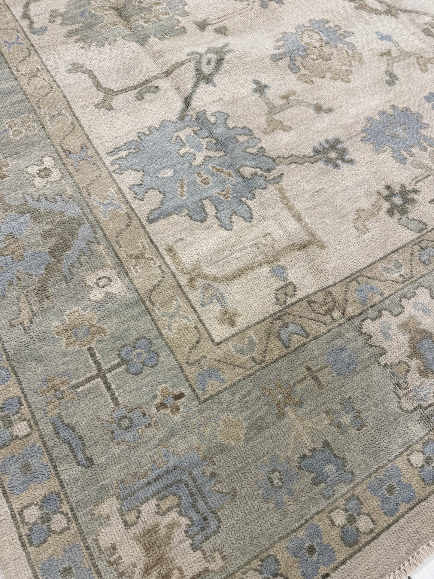 Close-up Evangeline Warm Oushak 100% rug wool with floral designs in beige, blue, green, and brown.