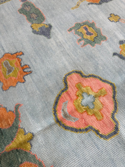 Layla hand-knotted wool modern Oushak rug in light blue with chartreuse, green, coral, and periwinkle