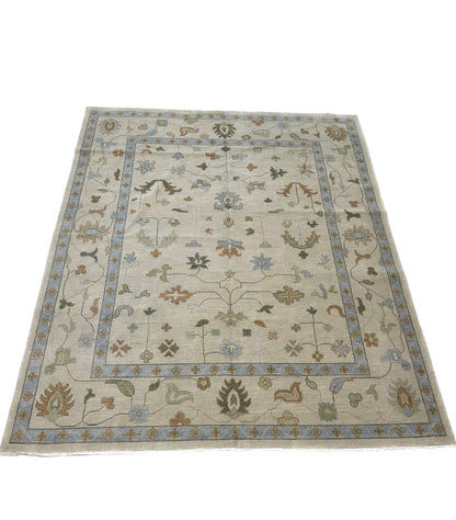 Ruth hand-knotted wool modern Oushak rug, ivory and tan base with light blue, muted green, and rust
