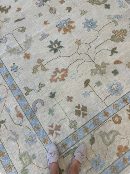 Ruth hand-knotted wool modern Oushak rug in ivory and tan with light blue, green, and rust tones