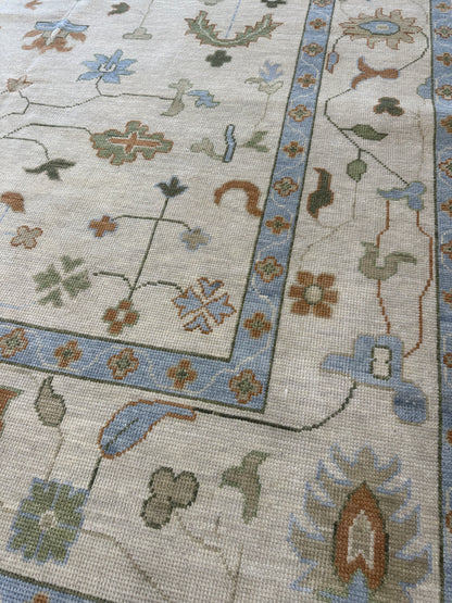 Ruth modern Oushak rug, ivory and tan with light blue, muted green, and a rust orange pop