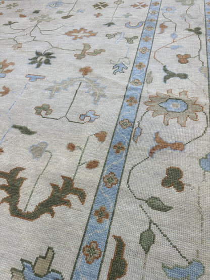 Ruth modern Oushak rug in ivory and tan with light blue, muted greens, and rust orange, hand-knotted wool