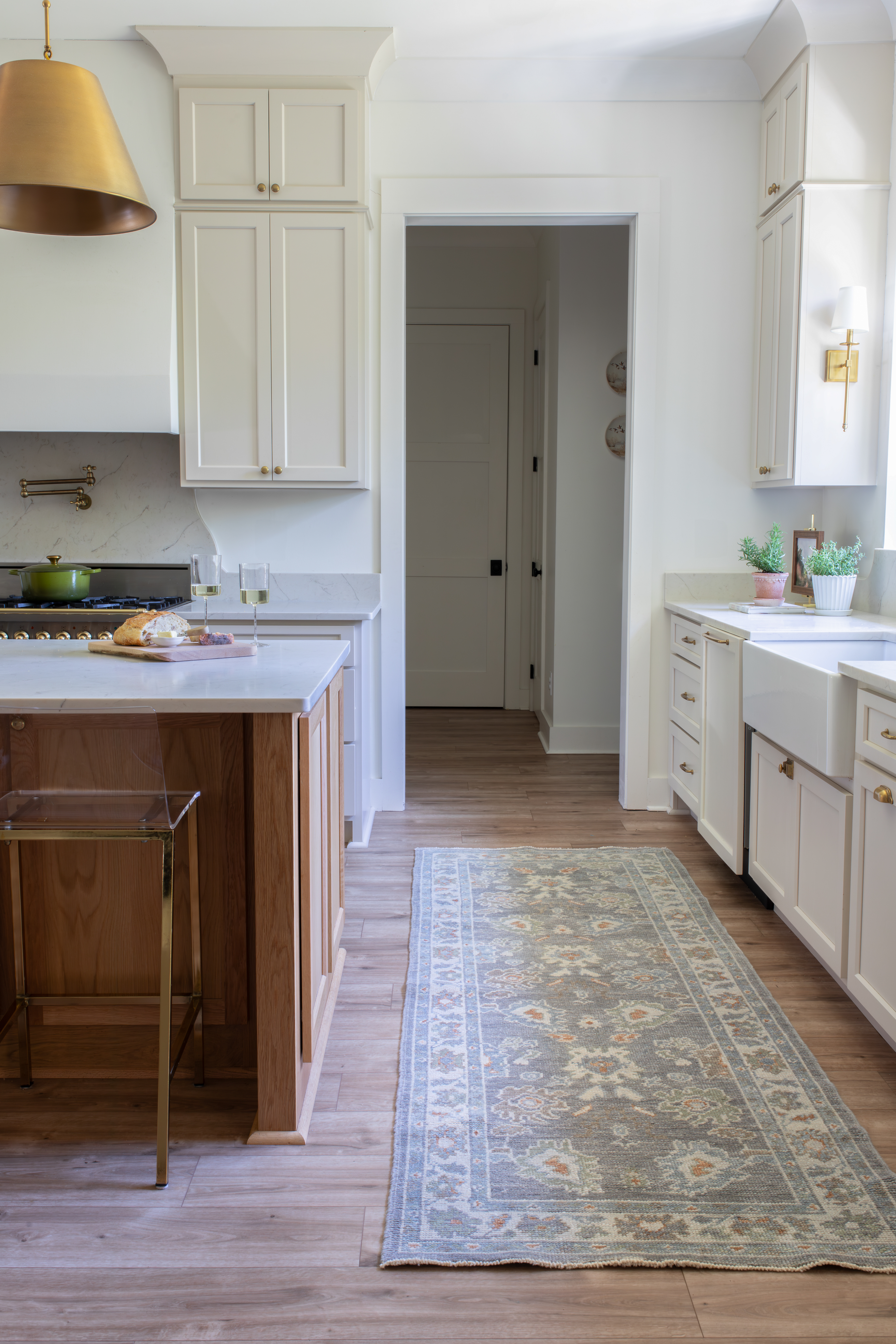 Gorgeous hand-knotted Turkish oushak rug in runner form in front of farmhouse kitchen sink.