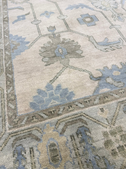 Close up of Laurel geometric modern Oushak rug featuring a cream base with a soft seafoam border and accents of green, tan, and dusty blue, hand-knotted wool rug by Vintage Rugs by the Bay.