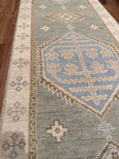 Lennon Blue and green 100% wool Modern Oushak runner with neutral border and green accents and blue center medallion on wood floor