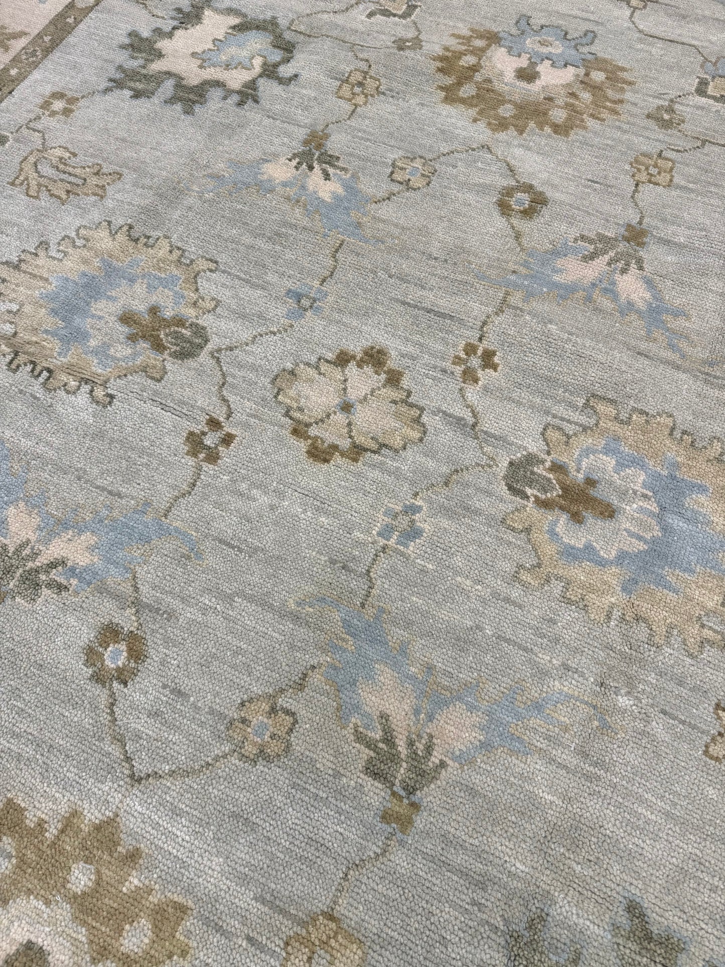 Close up of the middle of a Sage Green Modern Oushak hand-knotted wool rug with blues, greens, creams and browns