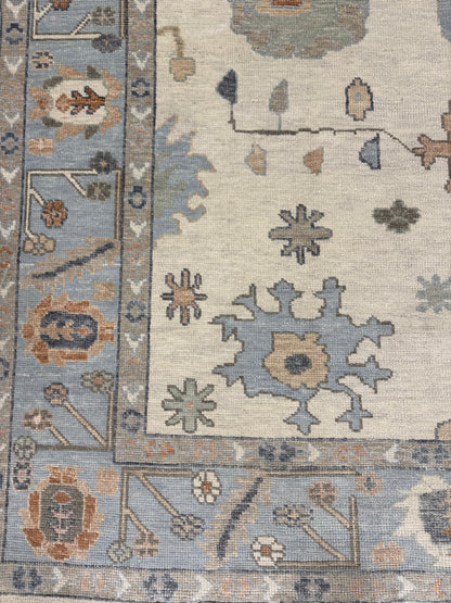 Close-up of Lottie Turkish Oushak hand-knotted wool  rug with geometric designs in blue, beige, orange, coral, cream and brown.