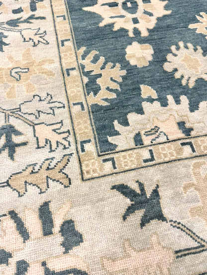 Close up of Lucille modern oushak rug features a dark turquoise base, seafoam border, and cream and tan accents. 