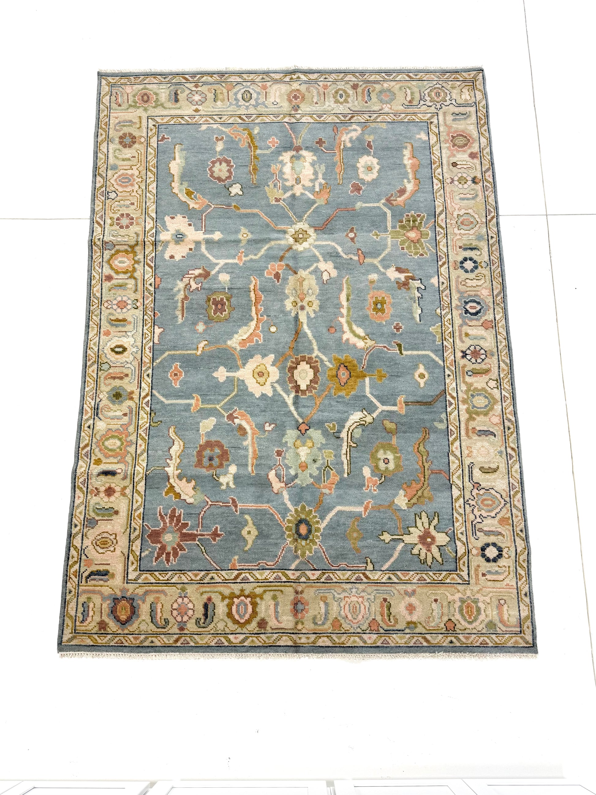 Full picture of blue modern oushak handknotted rug with accents of green, aqua, purple, brown, green.
