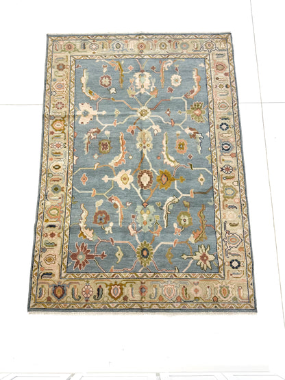 Full picture of blue modern oushak handknotted rug with accents of green, aqua, purple, brown, green.