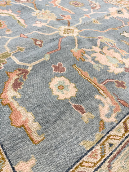 Close up of blue modern oushak rug with accents of aqua, salmon, green, brown