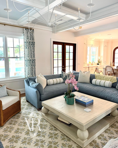 Penelope hand-knotted wool Oushak rug featuring a warm gray base with cobalt blue, chartreuse, soft gray, and subtle coral accents in a living room with a blue couch.