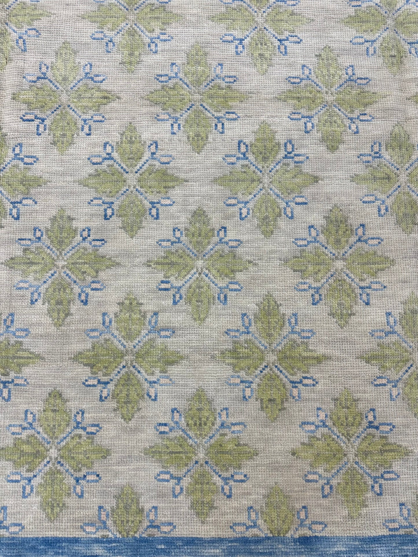 A hand-knotted wool modern Oushak area rug with a warm gray background and pops of color from cobalt blue, chartreuse, and light coral detail picture.
