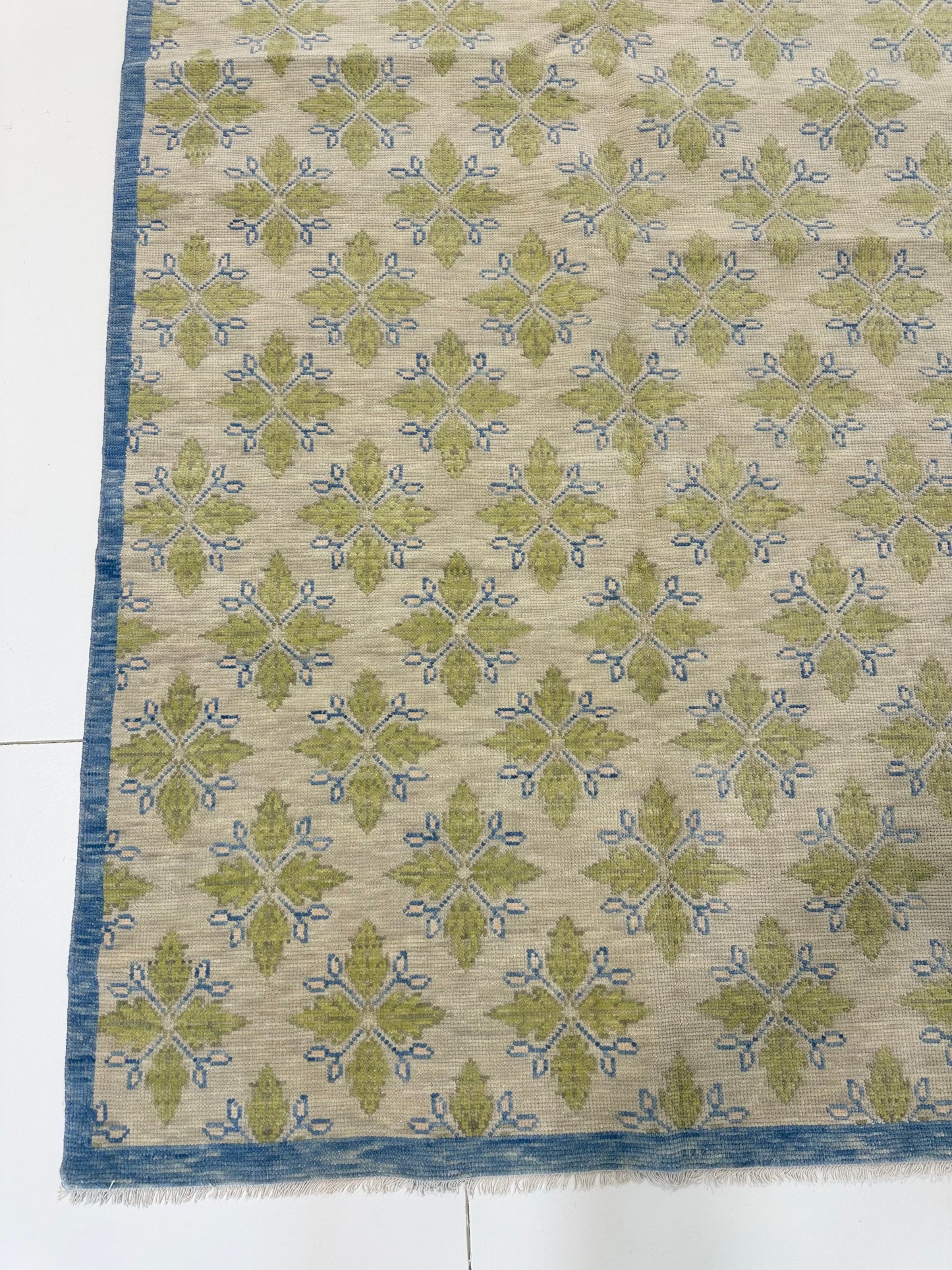 A 100% wool hand-knotted modern Oushak area rug with a warm gray background and pops of color from cobalt blue, chartreuse, and light coral.