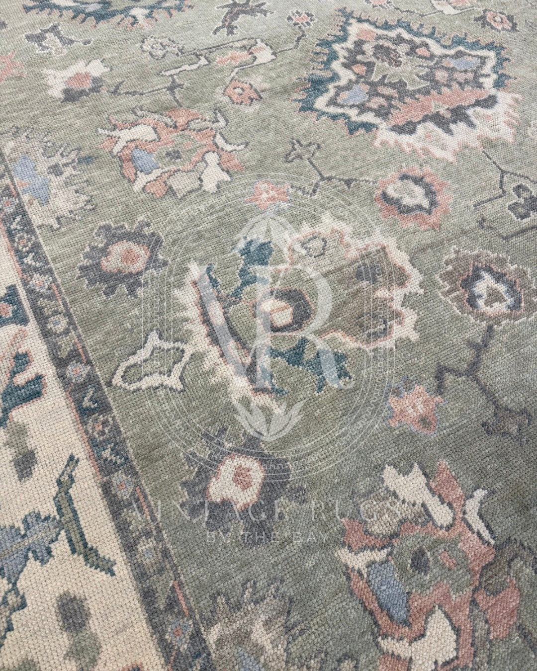 Close up of Gertrude Sage Green Turkish Oushak rug featuring a soft sage green base with accents of turquoise, salmon, cream, light blue, and gray in a timeless hand-knotted traditional pattern, perfect for living rooms, bedrooms, and elegant neutral interiors.