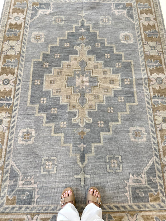 blue modern oushak rug named Susie with center medallion of slightly darker blue, tan, and pretty border that is brown with flower details located in Alabama