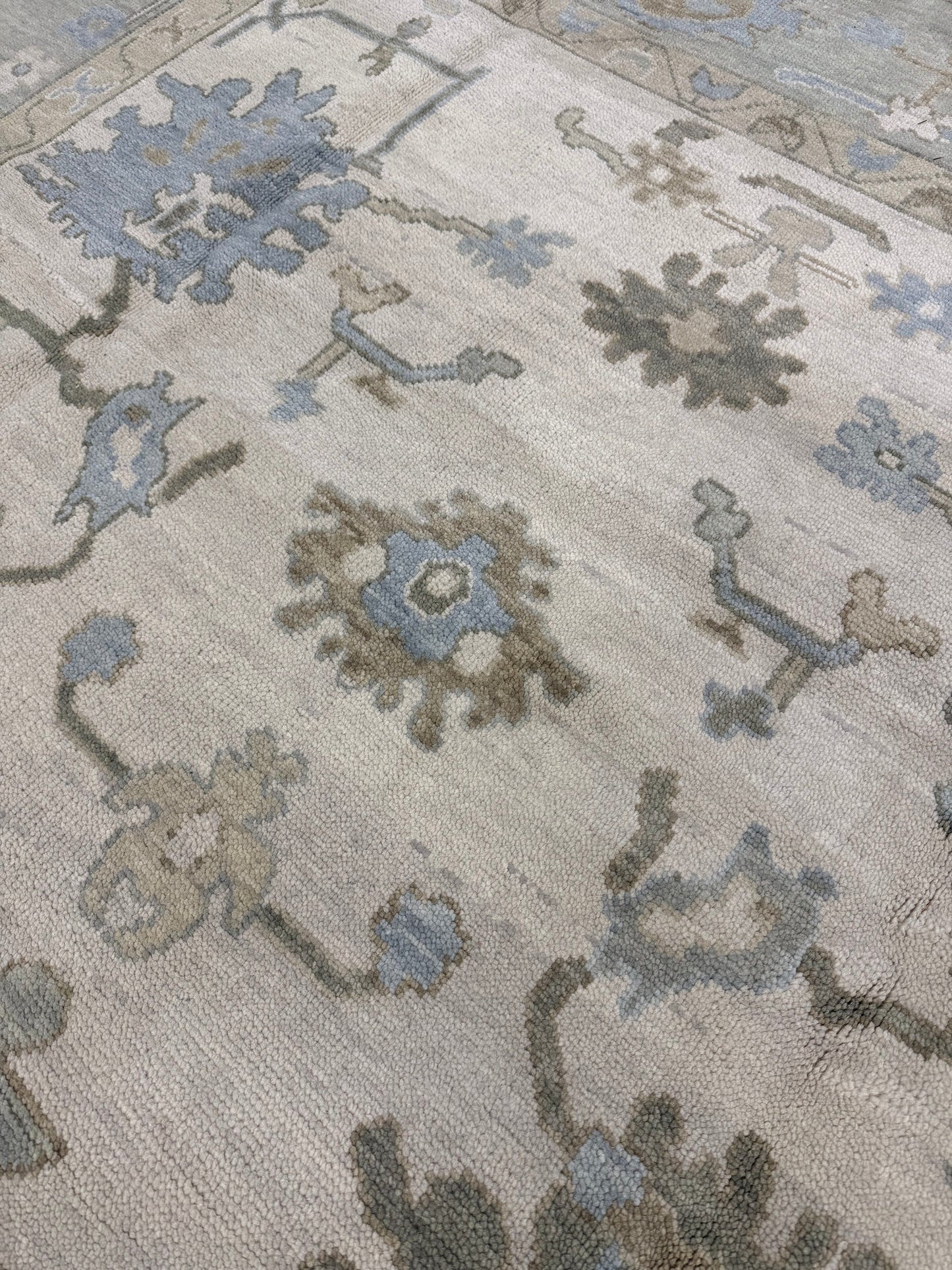 Close-up of Evangeline warm modern oushak wool rug with intricate designs in gray, blue, and beige.