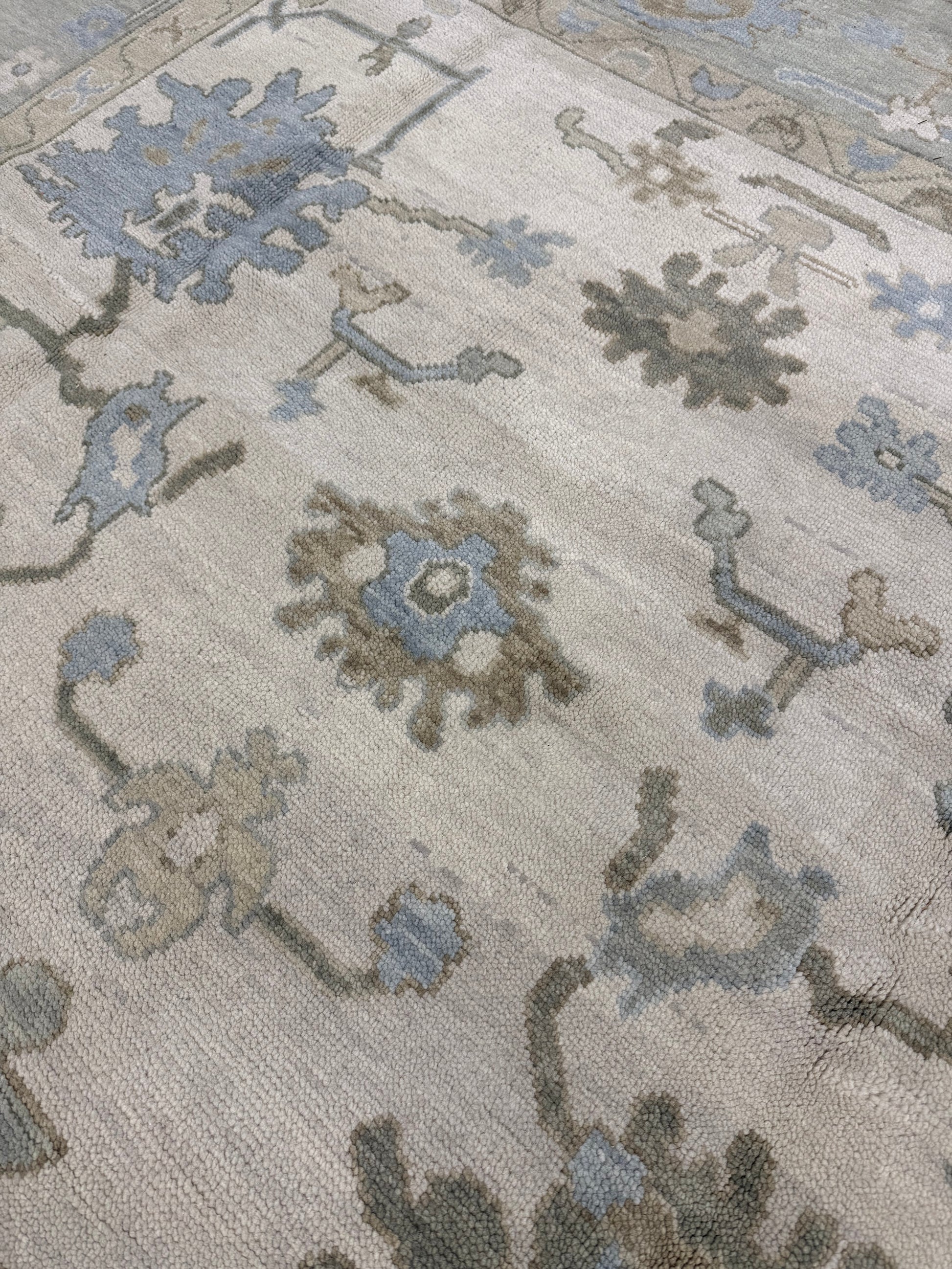 Close-up of Evangeline warm modern oushak wool rug with intricate designs in gray, blue, and beige.