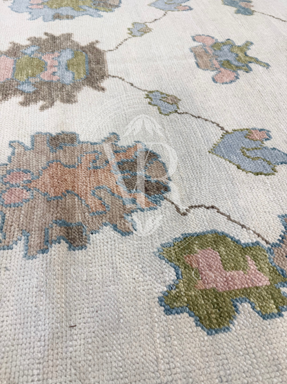 close up of Hand-knotted Palmer Turkish Oushak rug with a soft neutral base and matching neutral border colorful accents featuring turquoise, salmon, chartreuse, light blue, and warm brown accents in a modern, colorful pattern—perfect for living rooms, bedrooms, nurseries, and dining spaces.