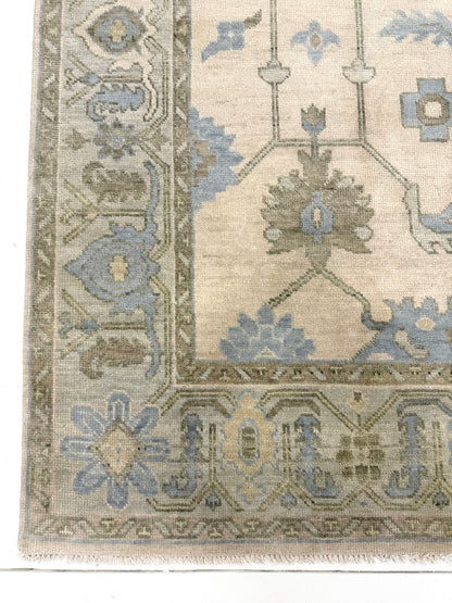 Corner of Laurel modern Oushak rug featuring a cream base with a soft seafoam border and accents of green, tan, and dusty blue, hand-knotted wool rug by Vintage Rugs by the Bay.