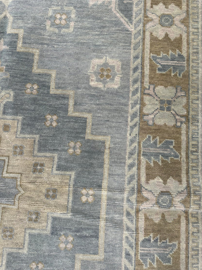 Susie hand-knotted wool modern Oushak rug in soft gray-blue with brown border and sage green and tan tones